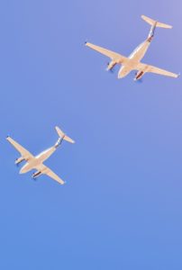 Two small aircrafts flying together in a blue sky