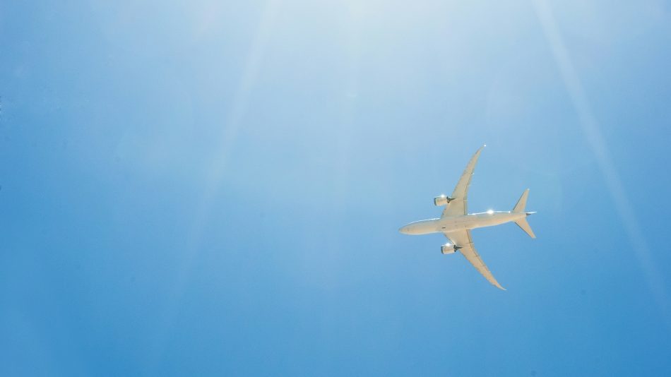 Passenger jet airplane flying on blue sky with sunlight